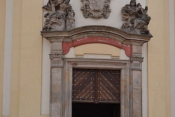 Nad vchodem do kostela jsou umístěny sochy Víry a Naděje a erb rodu Trauttmansdorffů (IČ)